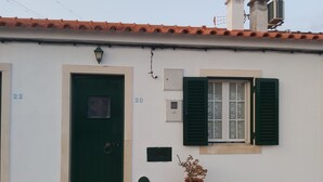 A building with numbered doors, a window with shutters, and a potted plant.