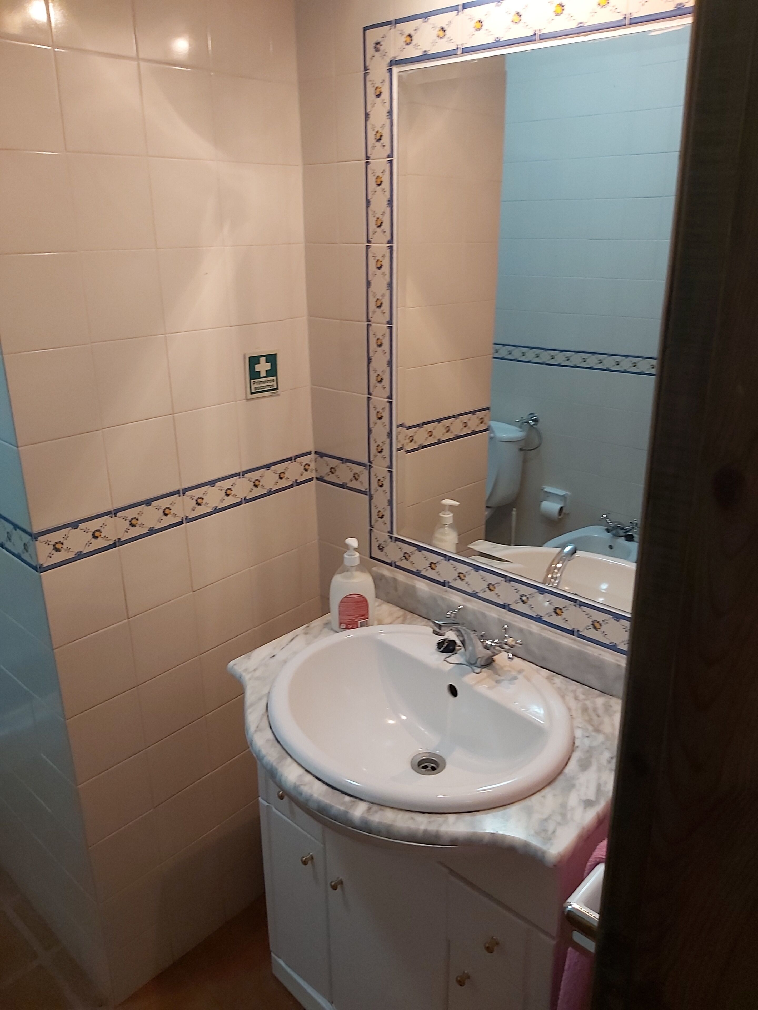 A bathroom with a white sink, a mirror, and a toilet.