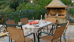 An outdoor patio with wicker chairs and a table set for dining, overlooking a lush landscape. - STUNNING TRANQUIL  VILLA WITH PRIVATE POOL CENTRAL LOCATION OF THE ISLAND (Sami)