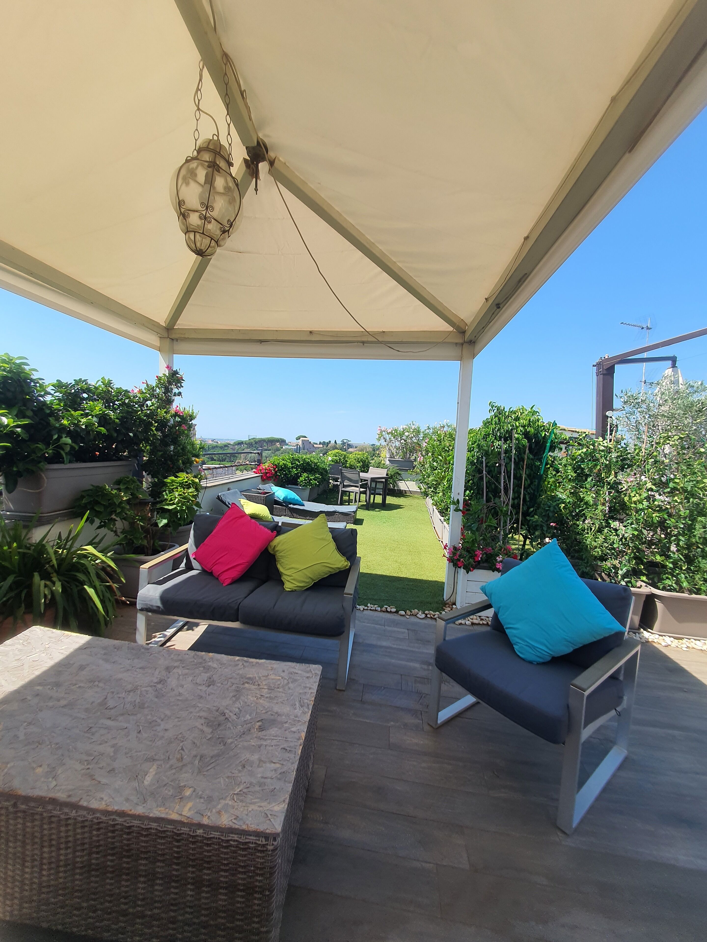 An outdoor patio with a covered seating area, a small table, and potted plants.