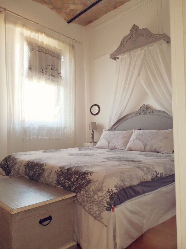 A bedroom with a bed, a bedside table, a nightstand, and a window with curtains. - SUPERACTIC APARTMENT WITH SPLENDID TERRACE ON THE COLOSSEUM, BREATHTAKING VIEW (Roma)
