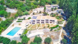 Eine Vogelperspektive zeigt ein Wohnanwesen mit Swimmingpool, mehreren Gebäuden und umliegender Grünfläche.