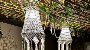 Un espace repas avec une longue table dressée pour un repas, agrémentée d’un centre de table et de lampes suspendues.