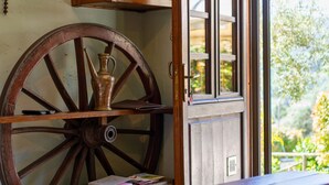 A rustic wooden cart with a brass pitcher, a wooden table with papers, and a window with a view of greenery. - Rustic house with private pool – exclusive use (San Martino in Freddana)