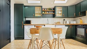 Una cocina con armarios verdes, una mesa de madera y una silla blanca.