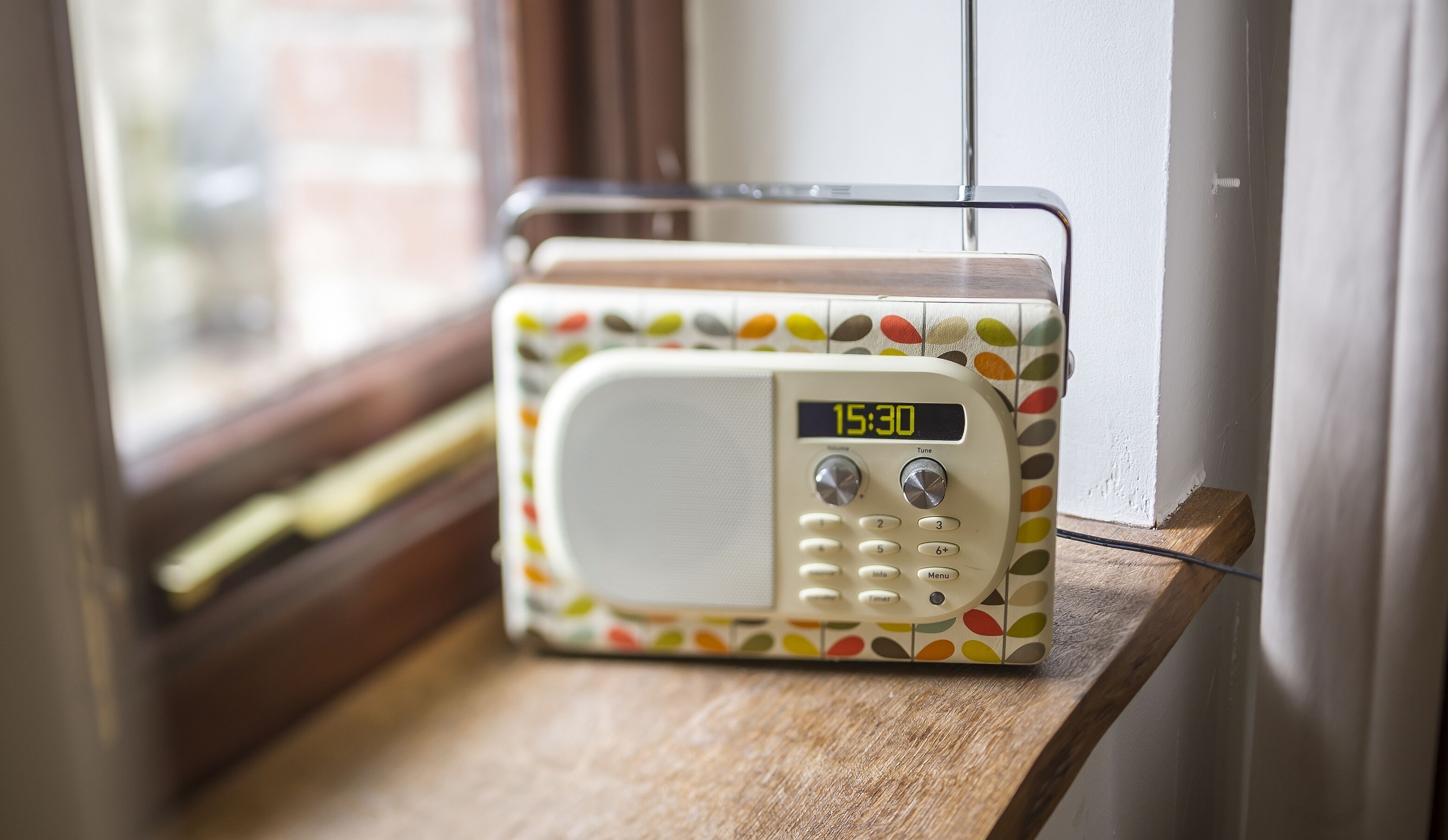 A radio on a wooden shelf near a window.