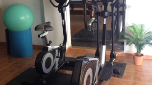 A gym with stationary bikes, a blue exercise ball, and a potted plant. - Modern Villa With Stunning Mountain Views (Mogan)