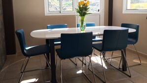 A dining area with a white table, blue chairs, and a vase with flowers. - Modern Villa With Stunning Mountain Views (Mogan)