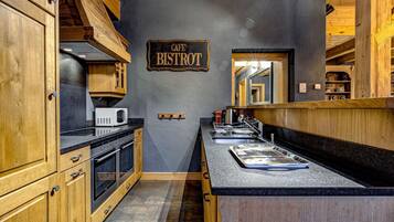 Une cuisine avec des meubles en bois, un four à micro-ondes, un évier et une enseigne indiquant « Café Bistro ».