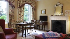 Una habitación con chimenea, televisión, una mesa de comedor con sillas y una cama con colcha.