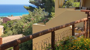 A balcony with a wooden railing, a view of the sea, and a garden with flowers. - Splendid Sea View Villa with Privacy and Garden, Just 700m from the Beach! (Costa Rei)