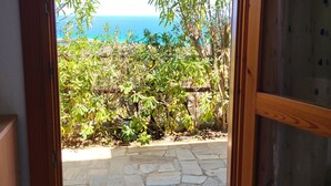 A doorway leading to a stone patio with a view of the sea and greenery. - Splendid Sea View Villa with Privacy and Garden, Just 700m from the Beach! (Costa Rei)