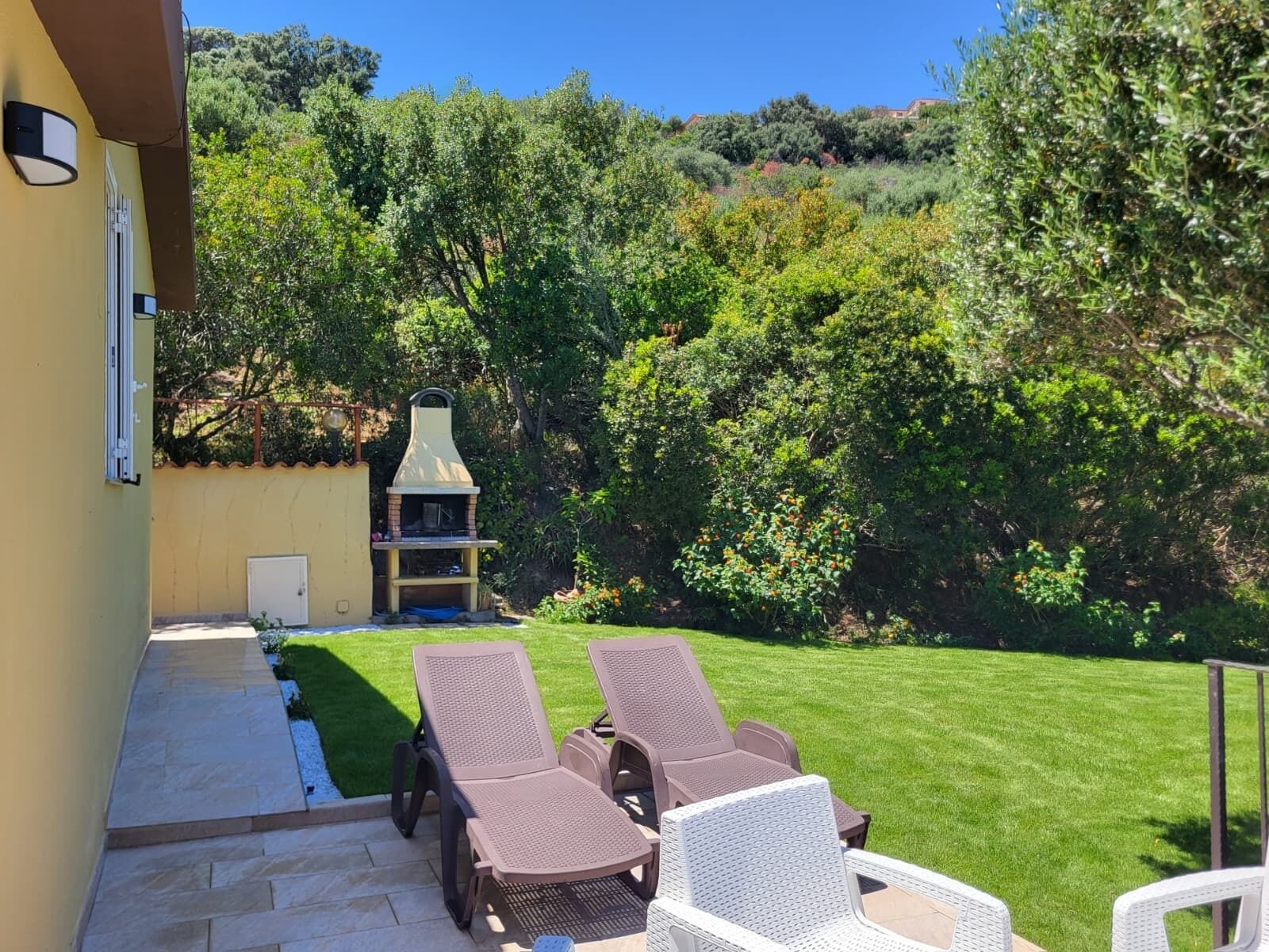 Een terras met twee loungestoelen en een barbecue.