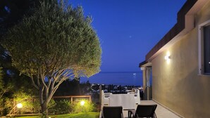 A patio with outdoor furniture, a tree, and a view of the sea at dusk. - Splendid Sea View Villa with Privacy and Garden, Just 700m from the Beach! (Costa Rei)
