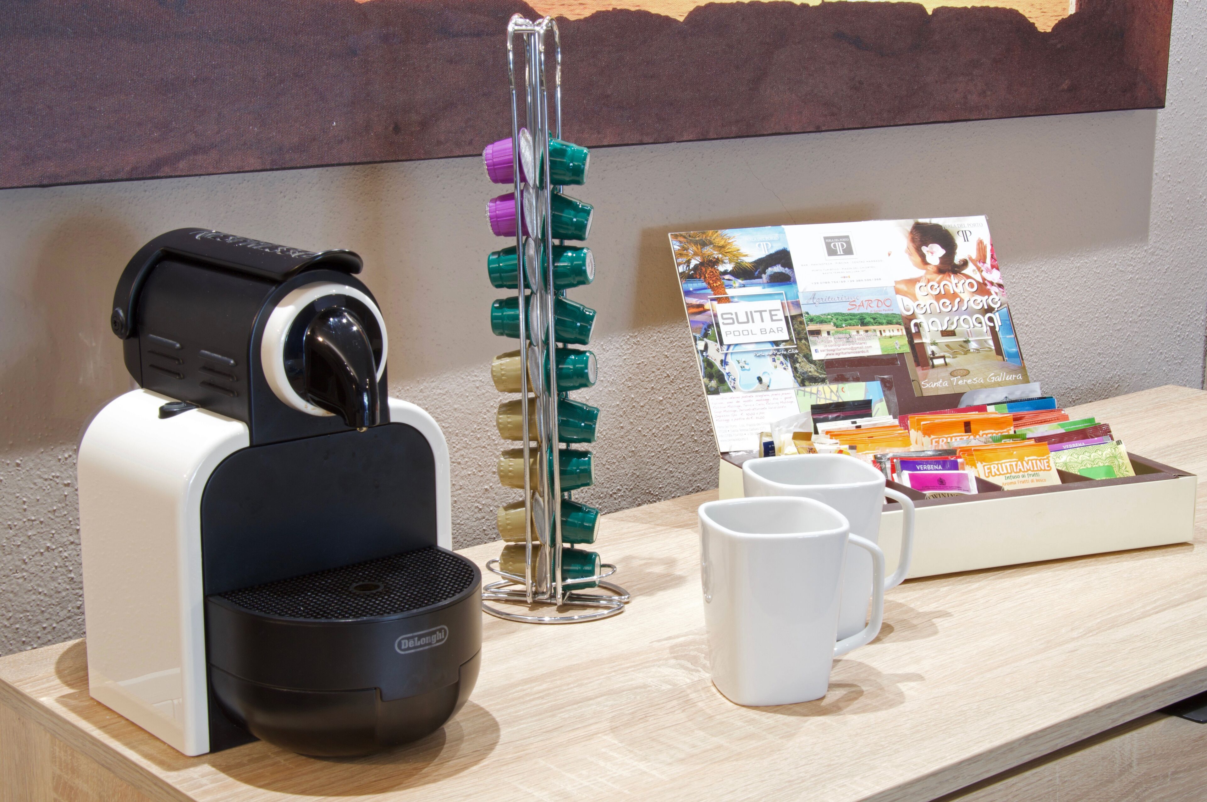 Une machine à café, un présentoir à magazines et un plateau rempli de cartes postales colorées sur une table en bois.