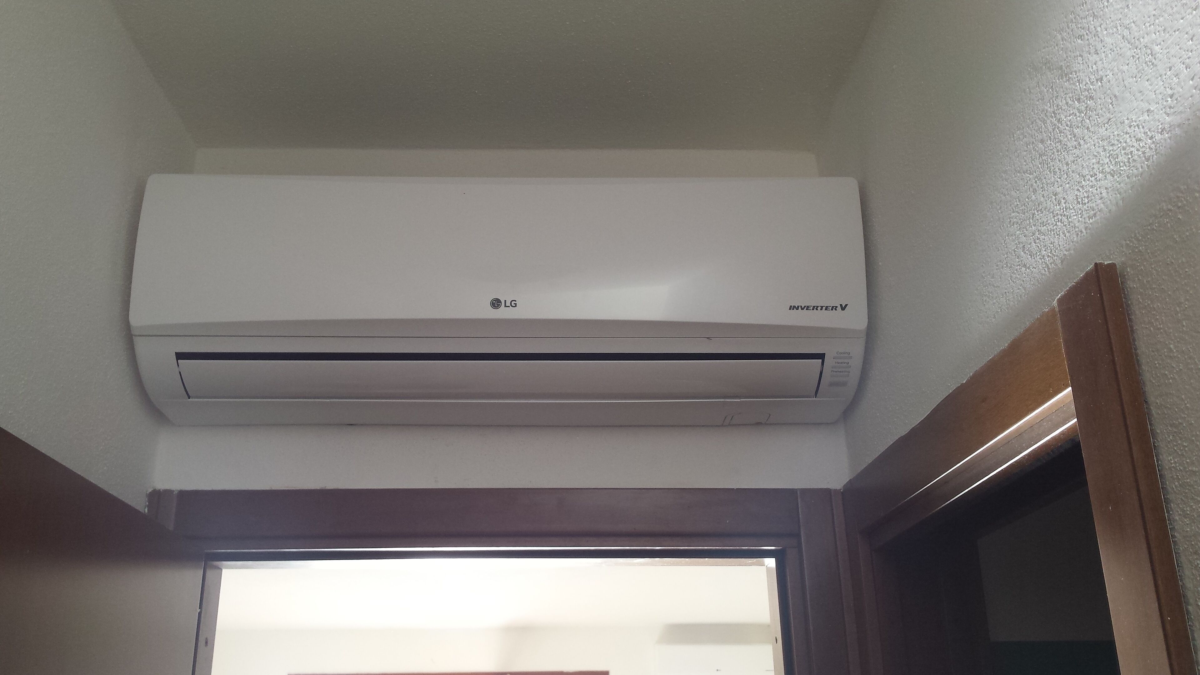 A white LG inverter V air conditioner mounted on a wall.