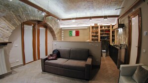 A cozy loft-style room with exposed brick walls, a built-in kitchen, and a seating area with a sofa and armchair. - Elegant house in the center of Rome-Parioli a stone's throw from Via Veneto (Roma)