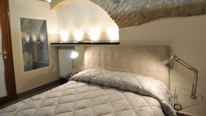 A bedroom with a brick ceiling, a bed with a quilted duvet, a bedside lamp, and a nightstand. - Elegant house in the center of Rome-Parioli a stone's throw from Via Veneto (Roma)