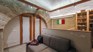 A cozy room with a stone archway, a wooden shelf with decorative items, and a sofa with a handbag on it. - Elegant house in the center of Rome-Parioli a stone's throw from Via Veneto (Roma)