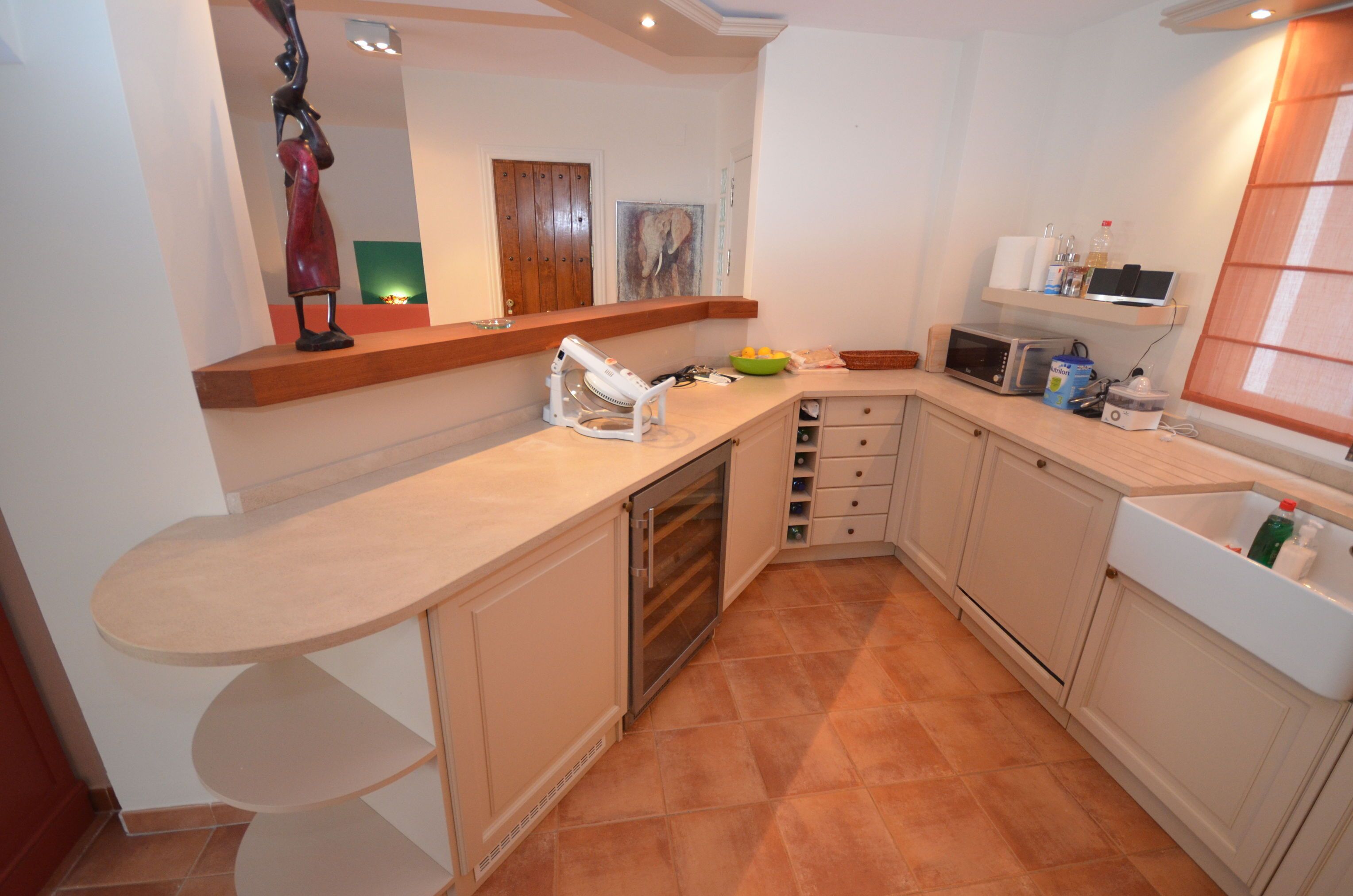 A kitchen with a curved countertop, a microwave, a sink, and a cabinet.