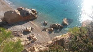 Un paysage côtier caractérisé par une eau d’un bleu limpide, un terrain rocheux et une végétation clairsemée.