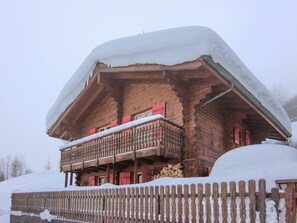Una cabaña de madera con balcón, rodeada de nieve.