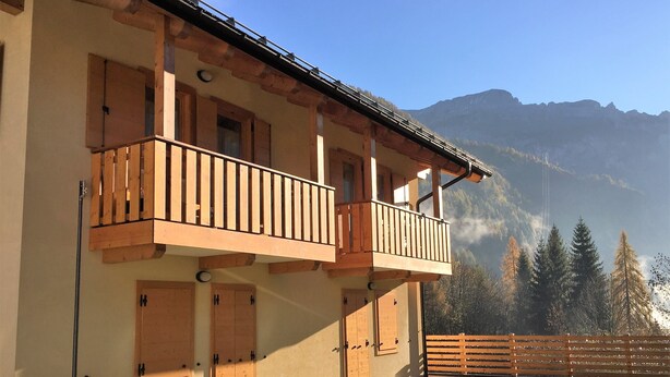 Un bâtiment à deux étages doté de balcons en bois, avec une chaîne de montagnes en arrière-plan.