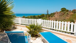 A pool area with a white fence, palm trees, and a view of the ocean. - PRIVATE POOL 3 BEDROOMS 3 BATHROOMS 150 MT FROM THE SEA WI FI FREE , CAR RENTAL (CASTELLAMMARE DEL GOLFO)