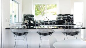 Una cocina moderna con tres sillas de estructura metálica, un ventanal grande y una encimera negra.