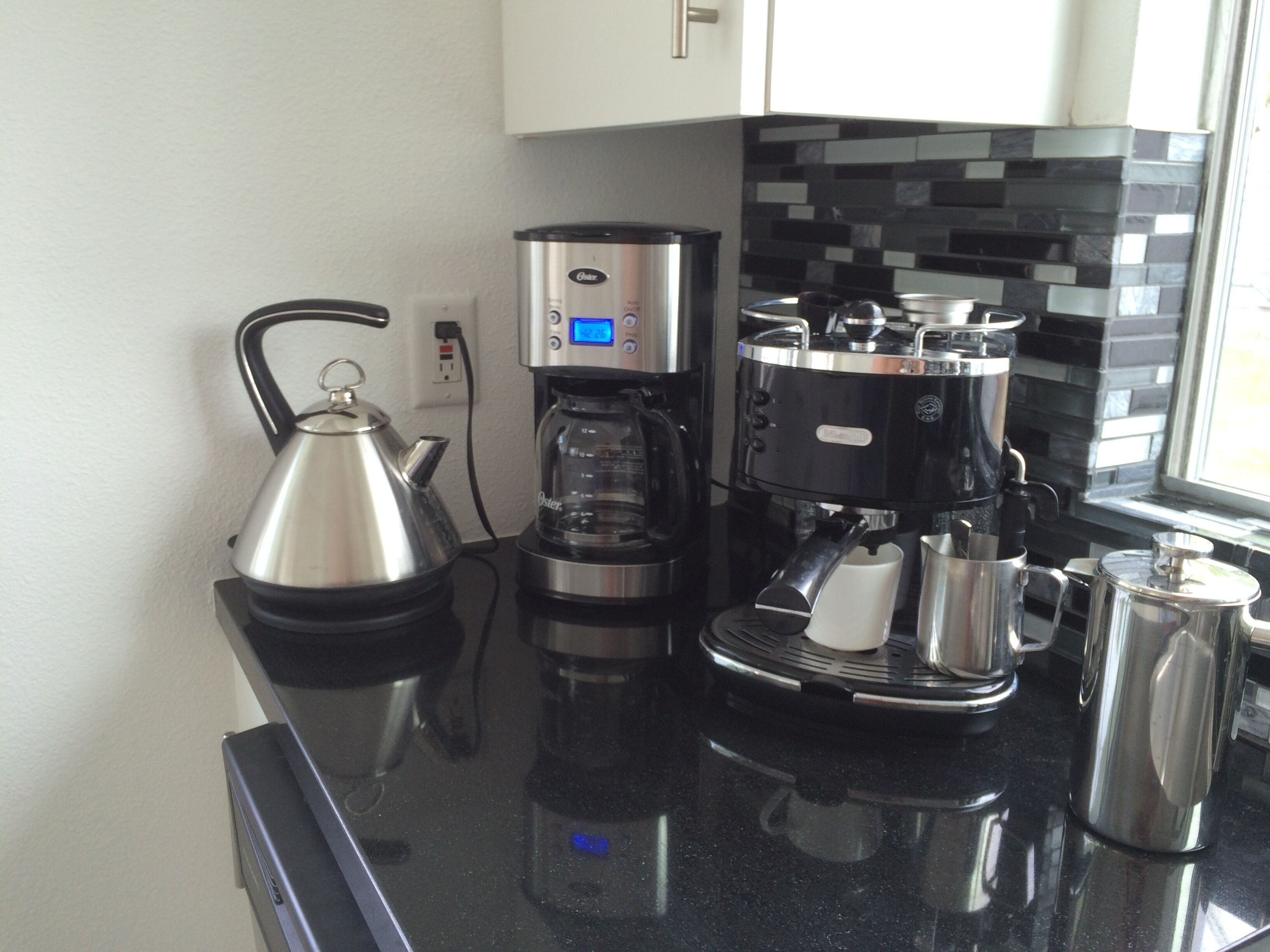 A modern kitchen with a coffee maker, kettle, and a coffee pot.