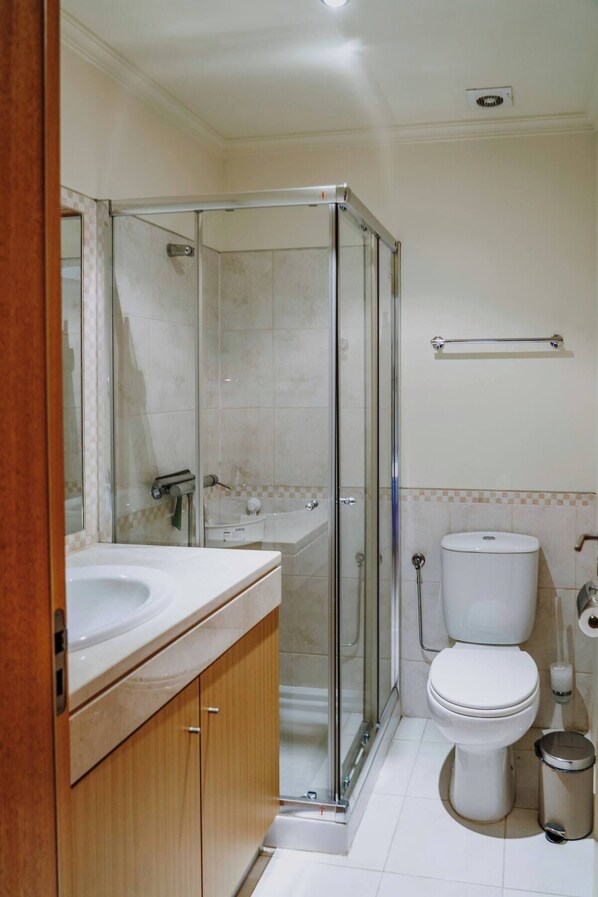 Une salle de bain avec une douche à parois de verre, un lavabo, des toilettes et un bidet.