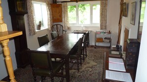A traditional dining room with a wooden table and chairs, a clock, and a window with curtains. - Tranquil country cottage set in the heart of a traditional family farm. (tenbury wells)