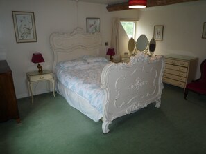 A bedroom with a large bed, two bedside tables, a dresser, a chair, and framed artwork on the walls. - Tranquil country cottage set in the heart of a traditional family farm. (tenbury wells)
