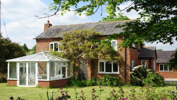 A traditional brick house with a conservatory, surrounded by a well-maintained garden with various plants and flowers. - Tranquil country cottage set in the heart of a traditional family farm. (tenbury wells)