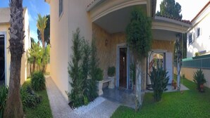 A residential property with a paved driveway, a covered entrance, and a well-maintained lawn. - Lagoa Albufeira House - with private swimming pool (Sesimbra)