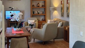 Een woonkamer met een bank, fauteuils, een salontafel en een boekenkast.