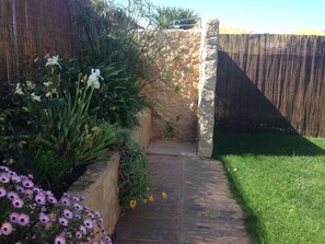A stone pathway leading to a wooden gate, surrounded by lush greenery and flowering plants. - VILLA With PRIVATE HEATED POOL; BBC; AirCon GARDENS; SAT./CABLE TV; PARKING WIFI (Portelas, Lagos)