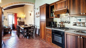 A kitchen with wooden cabinets, a gas stove, a coffee maker, and a sink. - Country-house with pool and Etna and sea views (Acireale)