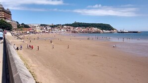 Une plage avec une vue sur la ville en arrière-plan, notamment une colline bien visible surmontée d’une tour.