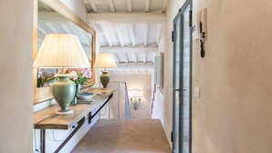 Un couloir avec un banc en bois, deux lampes, un miroir et une porte.