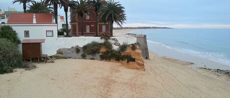 A beachside property with a white building, red roof, and palm trees.