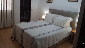 A bedroom with a bed, a nightstand, a lamp, a door, and two framed pictures on the wall. - Tourist Set Alporchinhos (Armação de Pêra - Algarve)