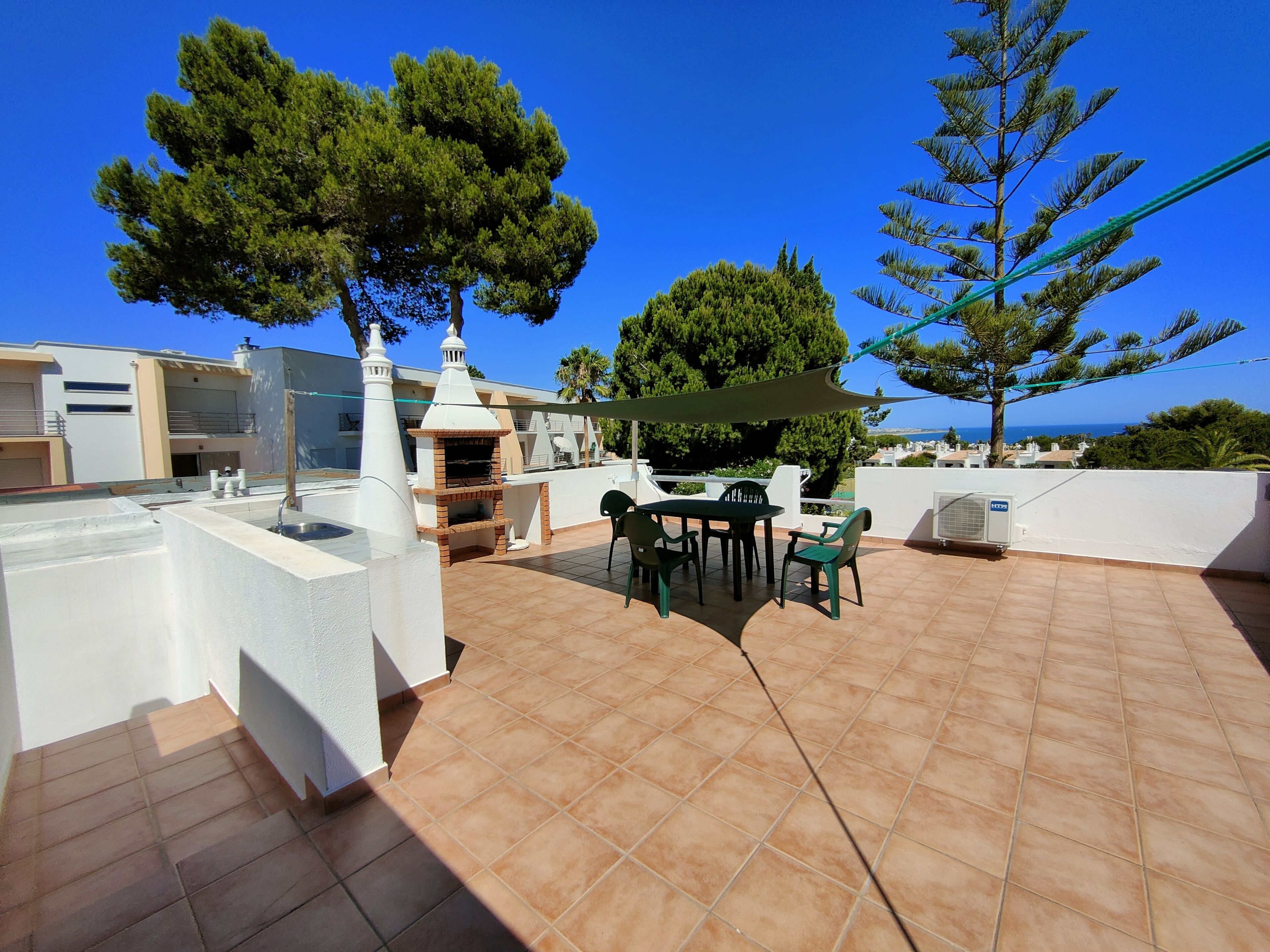 Una terraza en la azotea con zona de barbacoa, mobiliario exterior y vistas al mar.