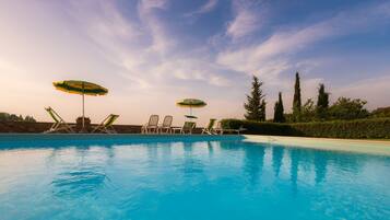 Una piscina al aire libre, sillones reclinables de piscina