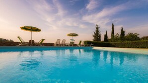 A swimming pool with lounge chairs and umbrellas.