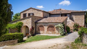A stone building with a tiled roof, arched windows, and a gravel driveway.