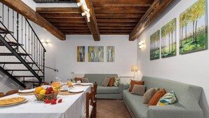 A dining area with a table set for breakfast, a staircase, and a green sofa.