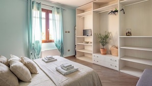 Une chambre à coucher avec un lit, une télévision, une plante en pot et une armoire.