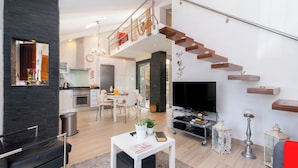 Ein modernes Wohnzimmer mit Treppe, Essbereich und Küche.