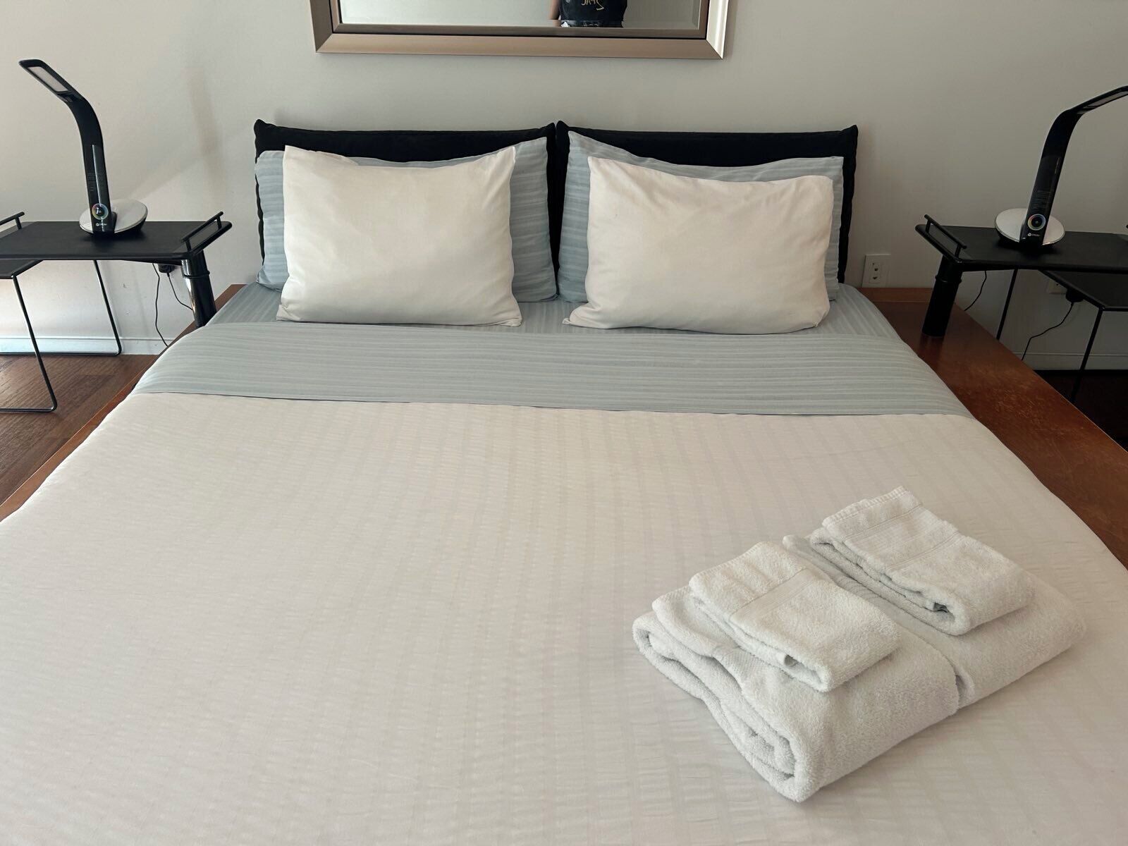 Una cama bien hecha con sábanas blancas, dos almohadas y una toalla doblada.